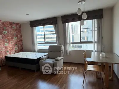 Spacious studio apartment with modern furnishings and large windows offering city views.