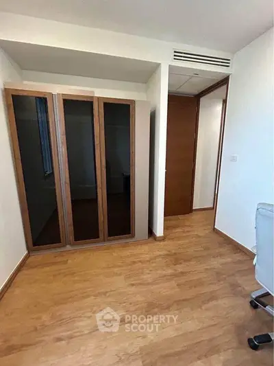 Spacious room with wooden flooring and modern wardrobe in a stylish apartment.