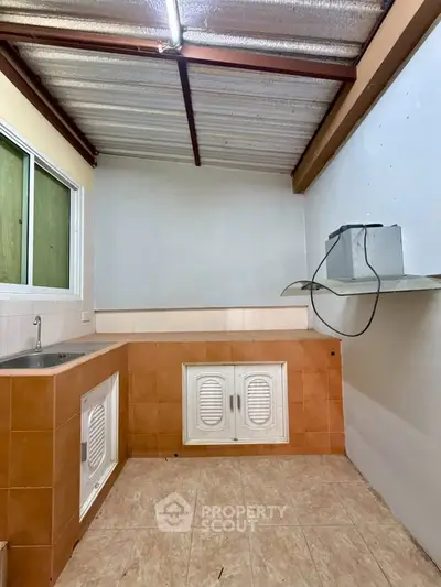 Spacious kitchen with tiled walls and modern sink, featuring a unique open layout and ample storage space.