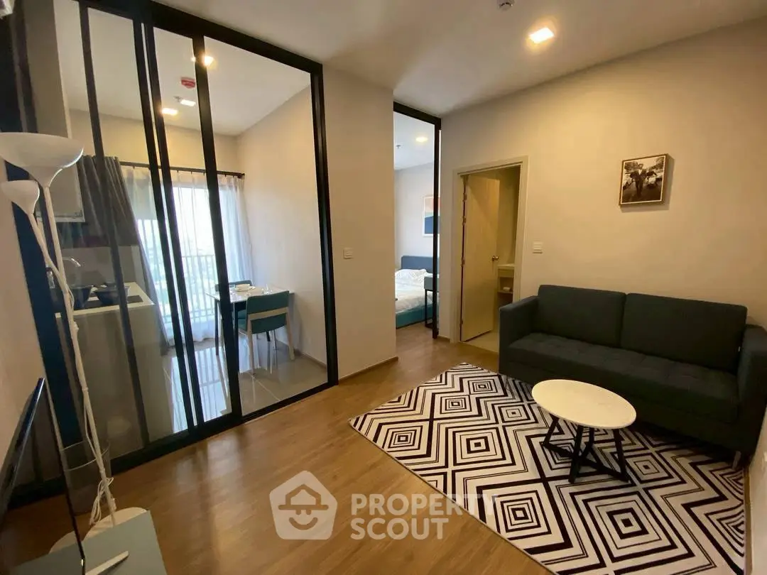 Modern living room with stylish decor and open layout, featuring a cozy sofa and geometric rug.