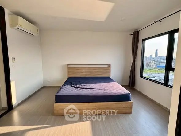 Spacious bedroom with large windows offering city views and natural light.