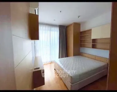 Spacious bedroom with large window and built-in storage in modern apartment.