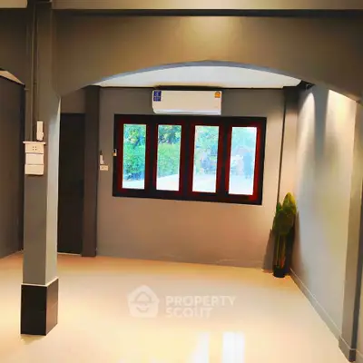 Spacious empty room with large window and air conditioning, perfect for customization.