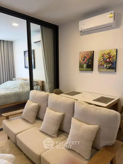 Modern living room with cozy sofa and adjacent bedroom in open-plan apartment