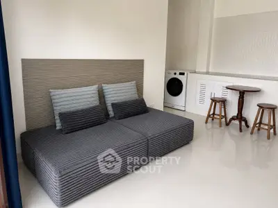 Modern living room with sleek sofa and washing machine in minimalist design