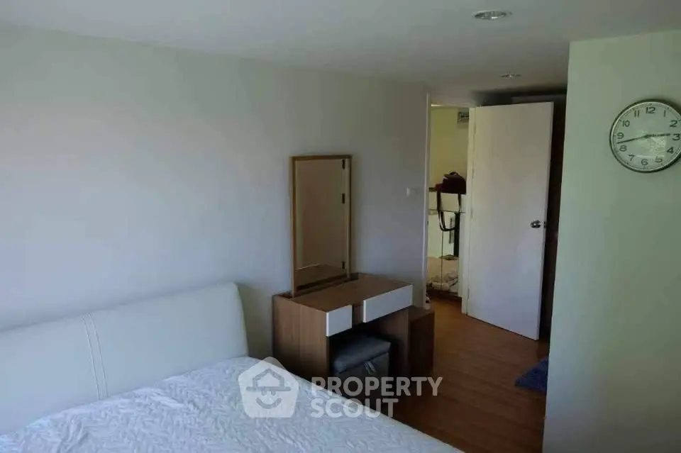 Cozy bedroom with modern furniture and wall clock, perfect for relaxation.