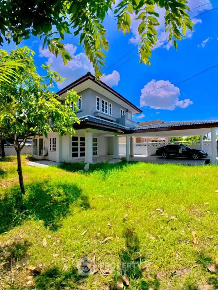 Charming two-story house with lush green lawn and carport under a vibrant blue sky.