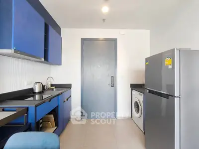 Modern kitchen with blue cabinets, stainless steel fridge, and washing machine in compact layout.
