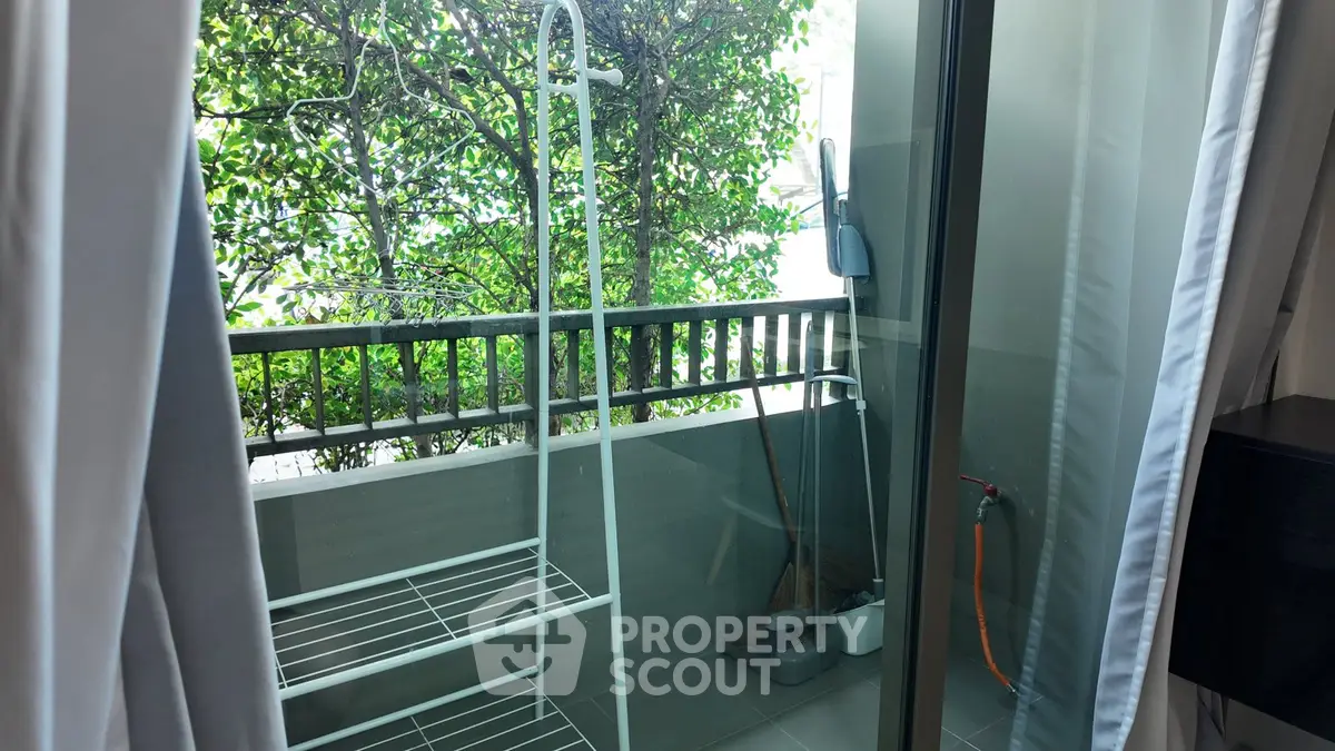 Charming balcony with greenery view and sliding glass door, perfect for relaxation.