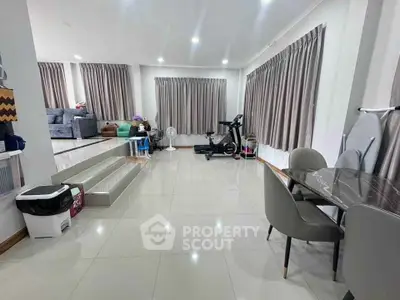 Spacious living room with modern decor and exercise equipment, ideal for family gatherings.