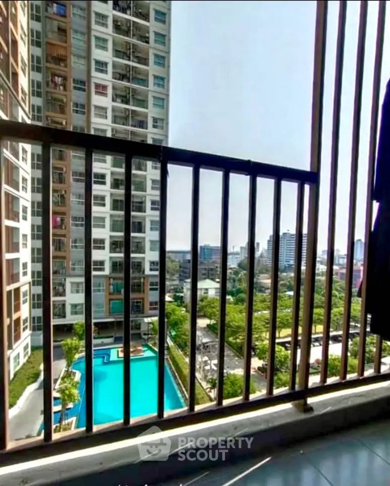 Stunning cityscape view from a high-rise balcony overlooking a pool and lush greenery.