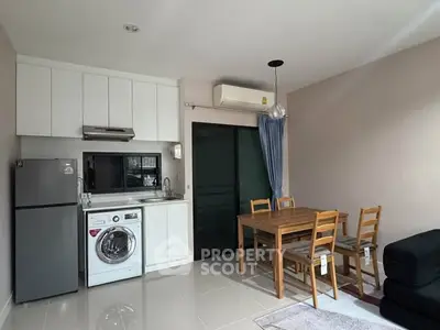 Modern kitchen with dining area featuring washing machine and sleek appliances.
