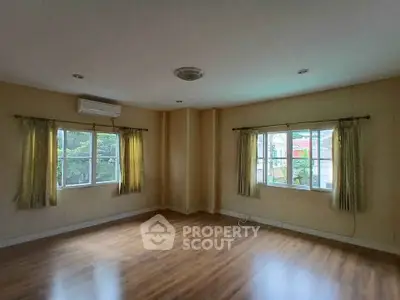 Spacious empty room with hardwood floors and large windows for natural light.