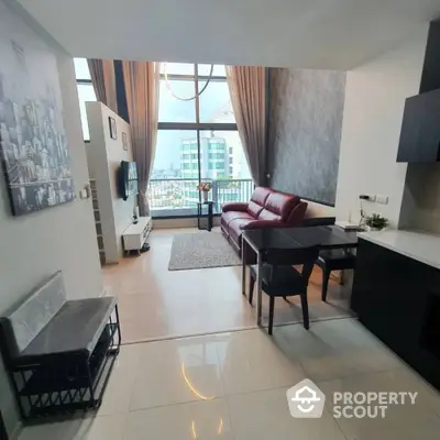 Modern living room with high ceilings and city view, featuring stylish furniture and elegant decor.