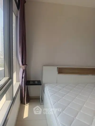 Bright bedroom with large window and modern decor in a high-rise apartment.