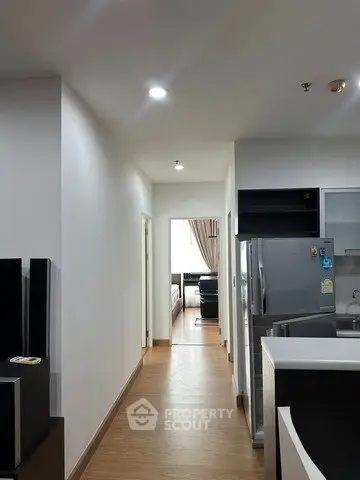 Modern apartment hallway leading to a cozy living room with sleek kitchen appliances.