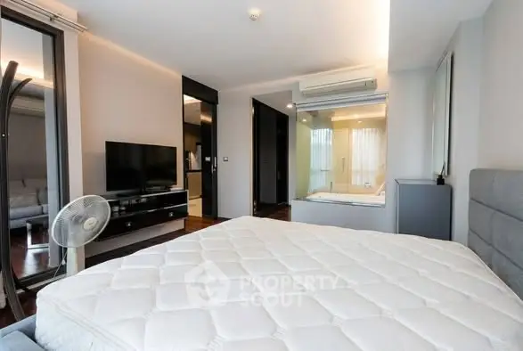 Modern bedroom with large window, TV, and air conditioning in a stylish apartment.