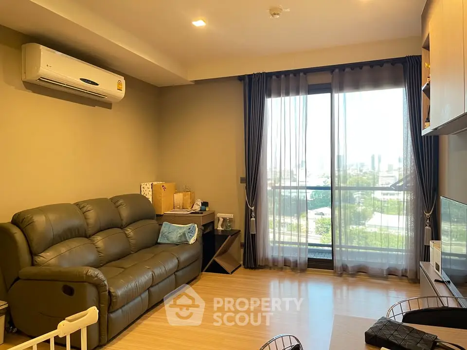 Modern living room with large window and comfortable seating in a stylish apartment.