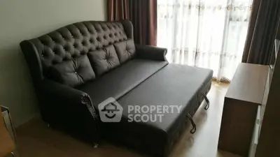 Elegant living room with a stylish dark leather sofa bed and natural light from large windows.