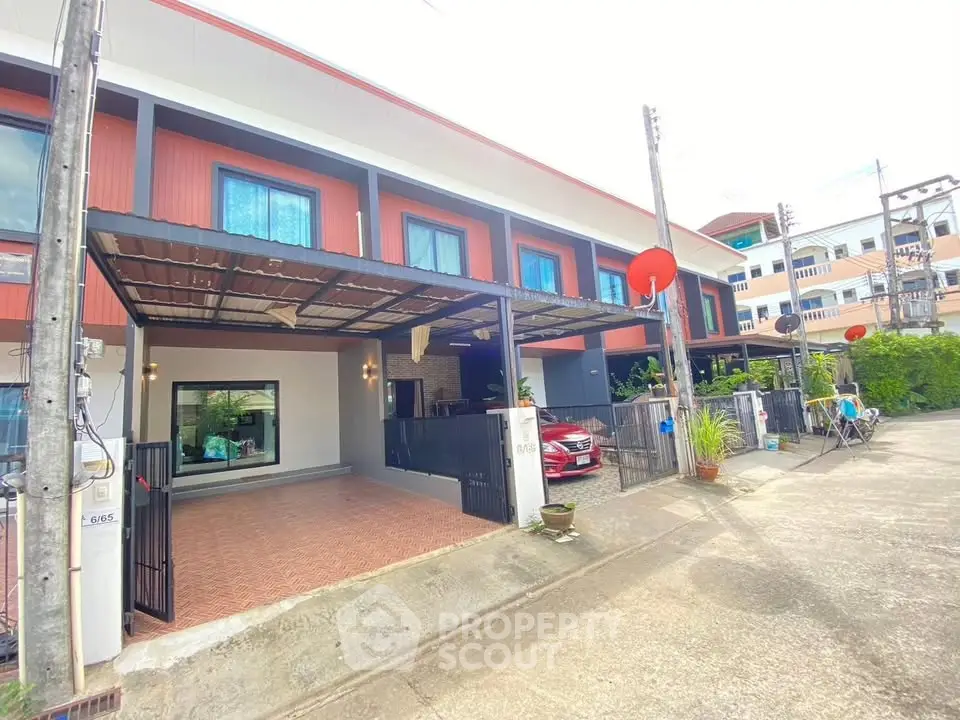 Modern townhouse exterior with carport and vibrant facade in a residential neighborhood.