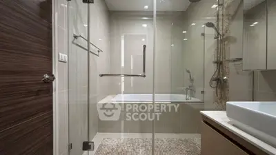 Modern bathroom with glass shower and bathtub in sleek design.
