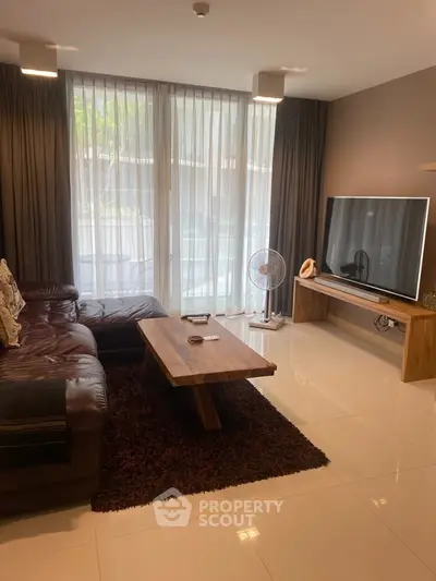 Spacious living room with modern decor and large TV, perfect for relaxation.