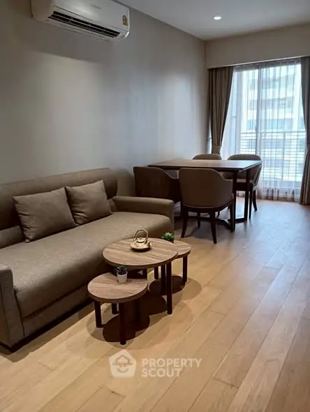 Modern living room with cozy sofa and dining area, featuring wooden flooring and natural light.