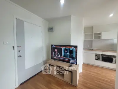 Modern apartment interior with open kitchen and cozy living area featuring a flat-screen TV.