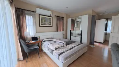 Spacious bedroom with modern decor and natural light, featuring a cozy workspace and elegant furnishings.