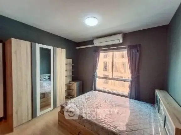 Spacious bedroom with large window and modern furnishings in a stylish apartment.