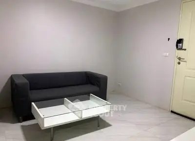 Minimalist living room with gray sofa and glass coffee table in modern apartment.