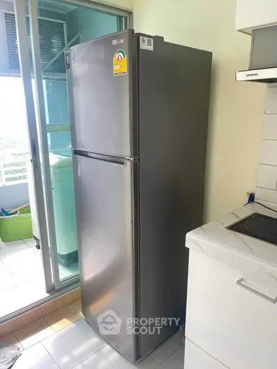 Modern kitchen with sleek stainless steel refrigerator and bright natural light.