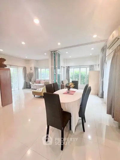 Spacious open-plan living and dining area with modern decor and large windows.