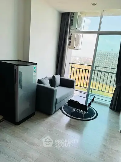 Modern living room with balcony view, featuring sleek sofa and compact fridge.