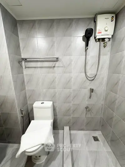Modern bathroom with sleek tiles and water heater, perfect for comfort and style.