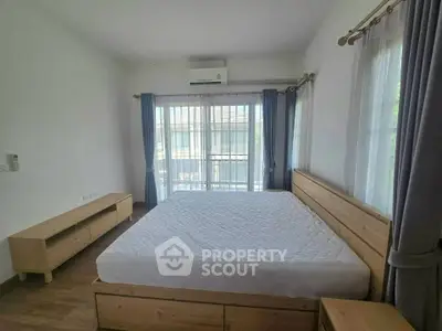 Spacious bedroom with large windows and modern wooden furniture