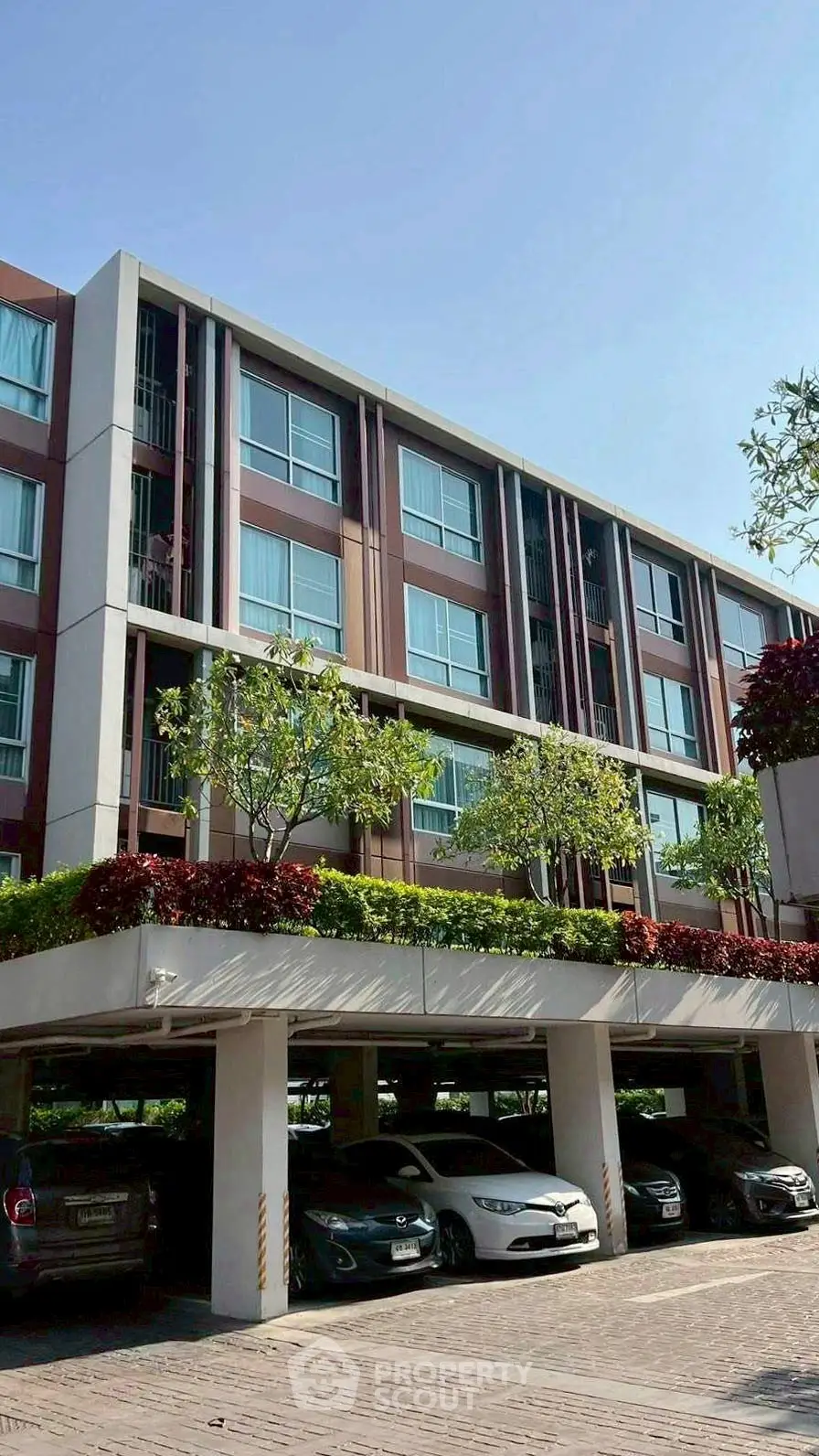 Modern apartment building with parking and lush greenery, perfect for urban living.