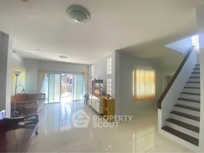 Spacious living room with natural light and modern staircase