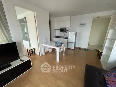 Modern apartment interior with open kitchen and cozy living area, featuring wooden flooring and minimalist design.