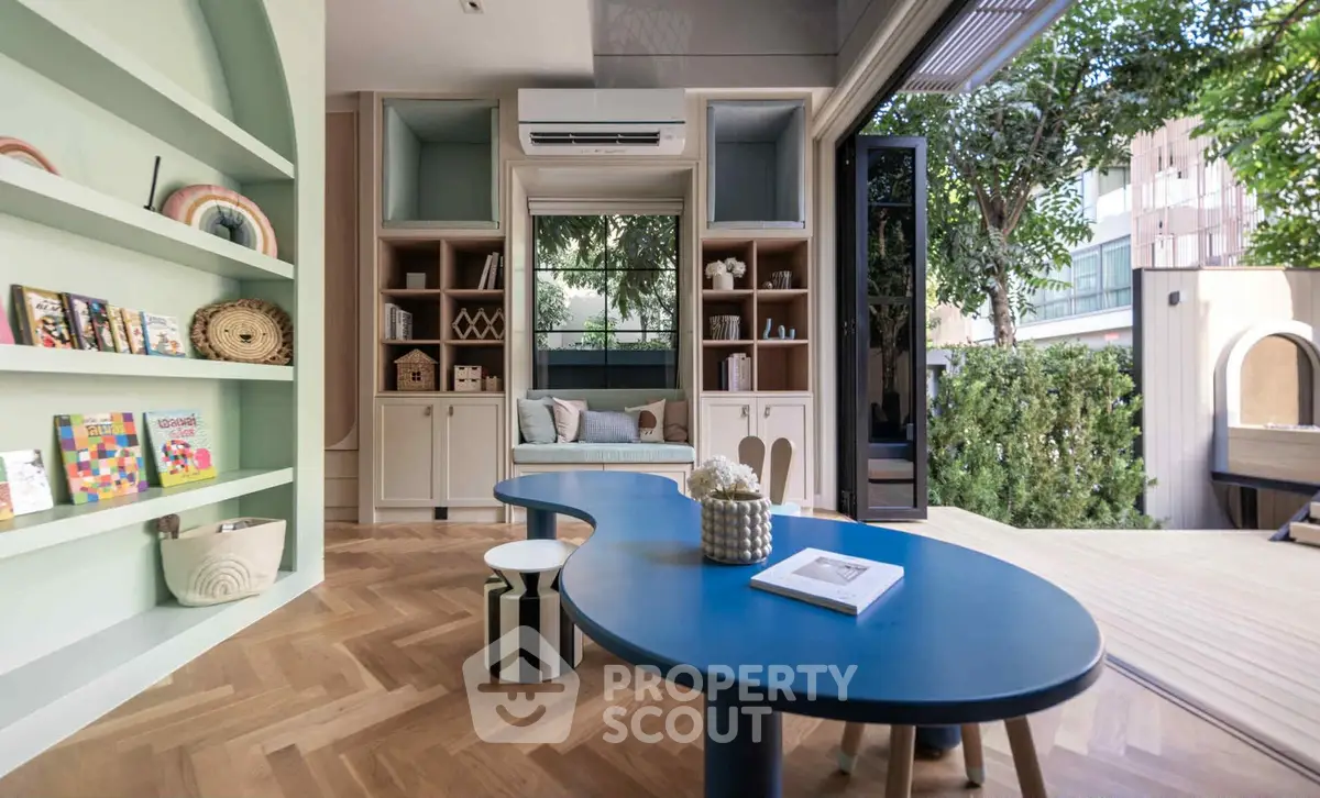 Stylish modern living room with unique blue table and open garden view.