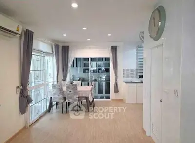 Spacious dining area with modern kitchen and large windows in a stylish home.