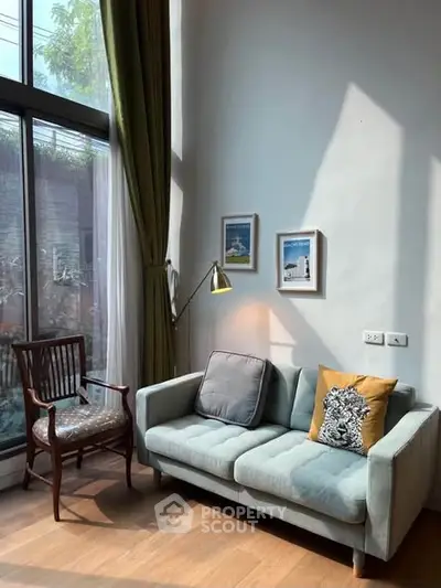 Charming living room with high ceilings, large windows, and cozy seating area, perfect for relaxation.