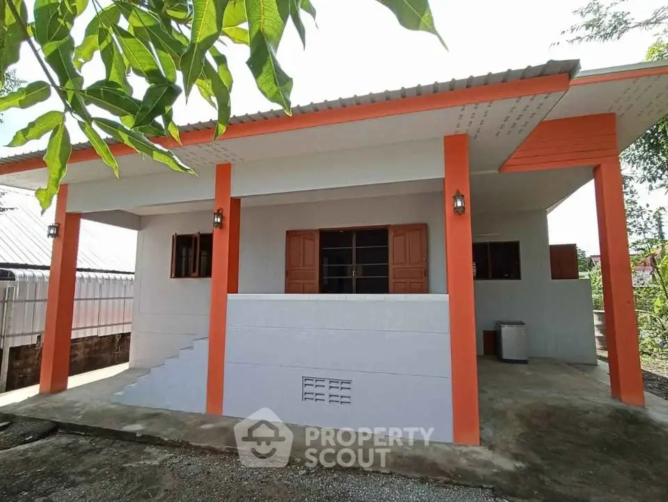 Charming single-story home with vibrant orange accents and spacious front porch.