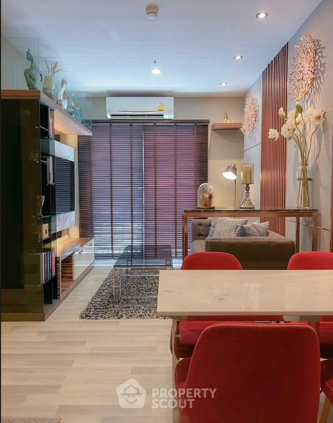 Modern living room with stylish decor and dining area, featuring red chairs and elegant lighting.