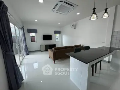 Modern living room with open kitchen, sleek design, and natural light