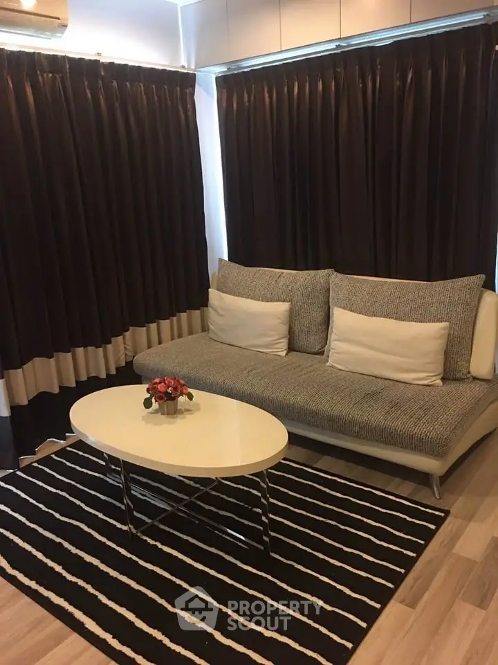 Cozy living room with modern sofa, stylish rug, and elegant curtains for a comfortable ambiance.