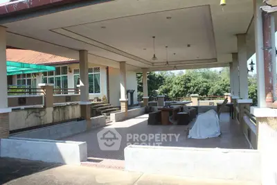 Spacious outdoor patio area with covered seating and lush greenery views.
