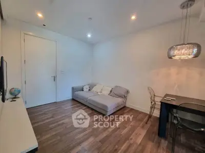 Modern living room with cozy sofa and elegant dining area, featuring stylish lighting and wooden flooring.