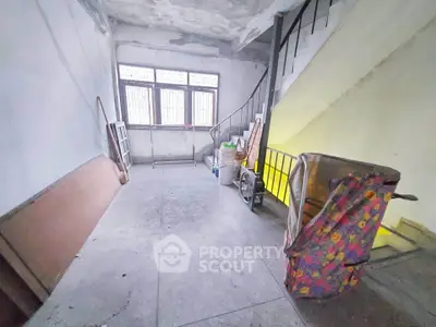 Spacious unfinished interior with staircase and large window, ideal for renovation projects.