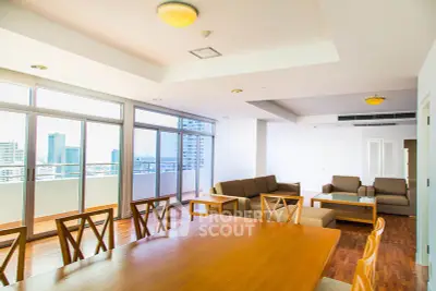 Spacious modern living room with large windows and city view, featuring elegant wooden furniture and ample natural light.